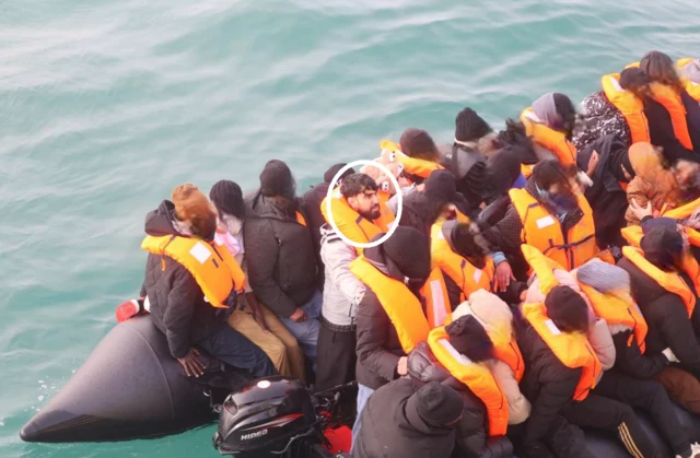 Mohammad Tajik on a boat full of people wearing life jackets.