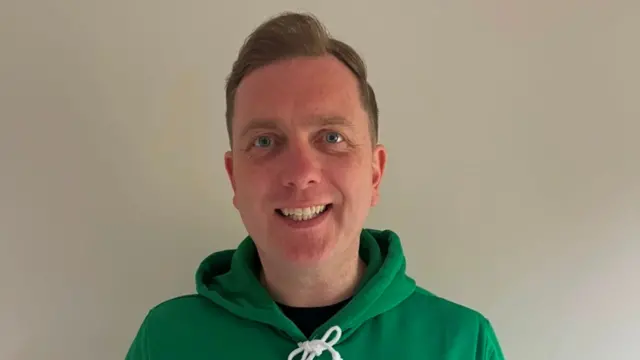 Man with light hair wearing green hoody