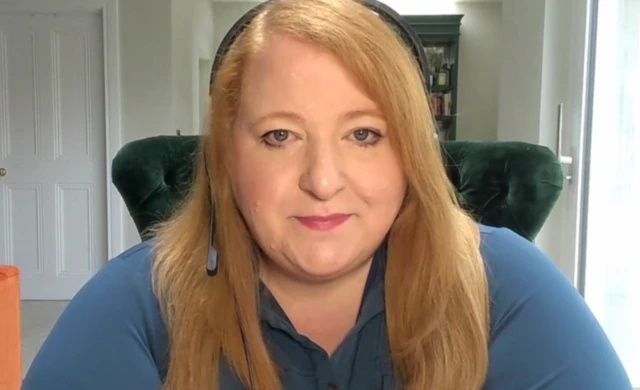 Northern Ireland Justice Minister Naomi Long sitting in her home office with a headset on.