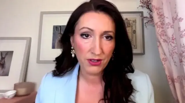Emma Little-Pengelly is pictured speaking to the BBC on a video livestream from what appears to be her home, with pictures on the wall in the background.