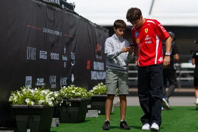 Charles Leclerc takes a picture with a young fan in the Barcelona paddock