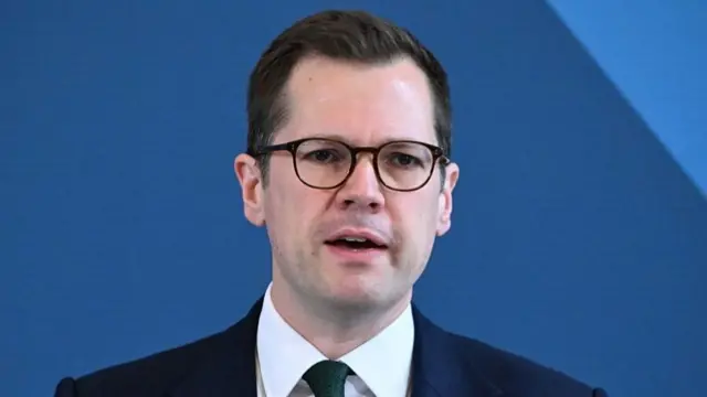 Headshot of Jenrick in front of blue background