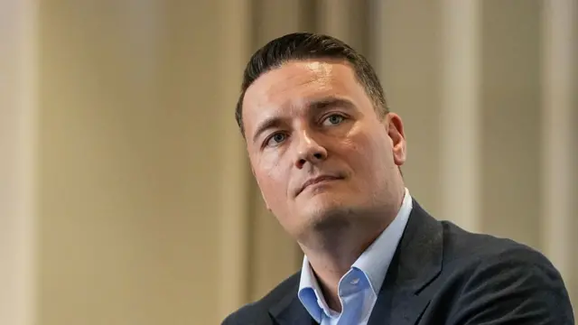 Headshot of Streeting looking up to the side in front of a blurry beige background