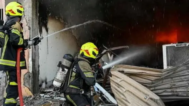 The aftermath of an Iranian drone strike on Bahrain, fire fighters using water canons