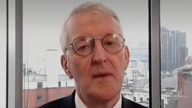 Hilary Benn, the UK secretary of state for Northern Ireland, speaking from an office with a city skyline in the background.