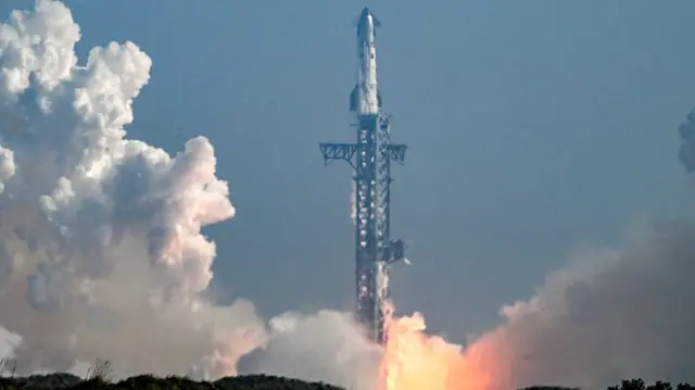 A rocket launching into the sky with red and white smoke surrounding it