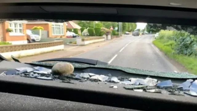 Rock seen on back of vehicle with glass shards visible