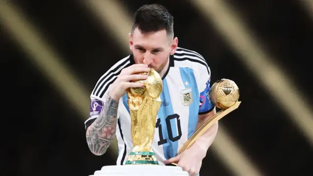 Lionel Messi placing a kiss on the World Cup trophy