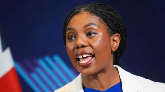 Conservative Party leader Kemi Badenoch delivers a speech in Westminster, against a blue background