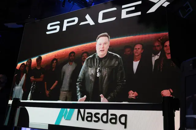 Elon Musk, founder and CEO of SpaceX, speaks via video before the ringing of opening bell at the Nasdaq Marketsite at the launch of the company's initial public offering (IPO) on June 12, 2026 in New York City. SpaceX is set to begin trading under the ticker SPCX following what is expected to be the largest initial public offering in history. Elon Musk, who also serves as chief executive of Tesla, could become the world's first trillionaire. In a filing with the Securities and Exchange Commission, the company said it plans to raise $75 billion by selling 555.6 million shares at $135 each.
