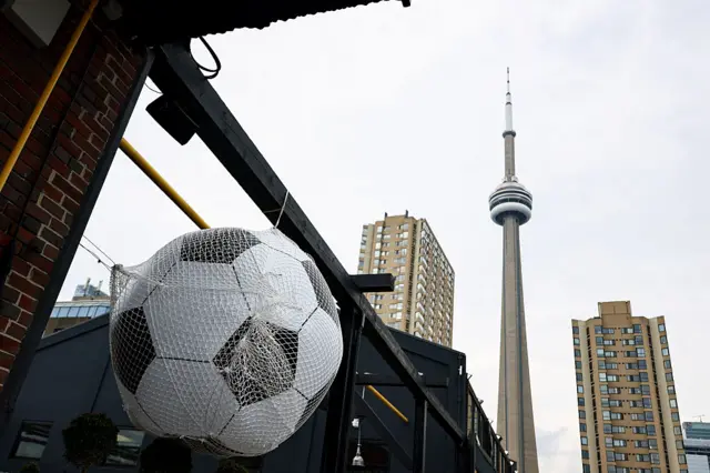 An oversized ball hangs from a rail with the CN Tower in the background