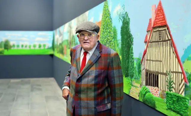 Hockney stands in front of his 'A year in Normandie' painting