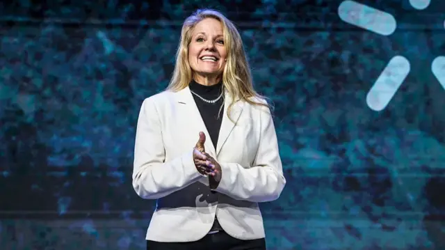 Gwynne Shotwell, chief operating officer of SpaceX, during a keynote speech at MWC Barcelona. She is wearing a white blazer over a black turtleneck and a necklace.
