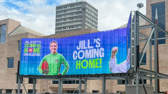 Massive electronic sign in a square which says "Jill's coming home" with a photo of Jill Scott