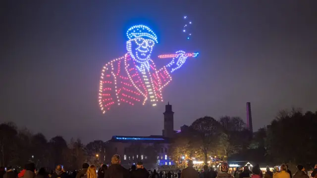 A depiction of artist David Hockney created with an array of illuminated drones adorns the sky above Salts Mill and Saltaire in Bradford