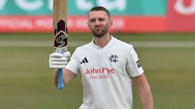Joe Clarke raises his bat to celebrate a century against Surrey on 8 May