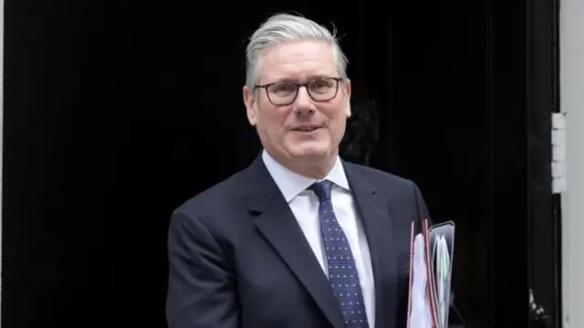 Keir Starmer smiles as he steps out of Downing Street holding two folders