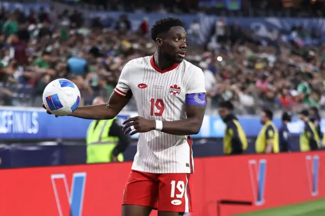 Alphonso Davies holding a football