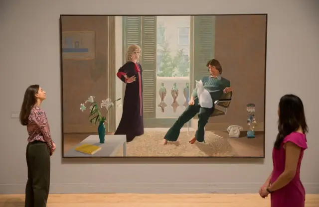 Two people look at at the painting 'Mr and Mrs Clark and Percy'