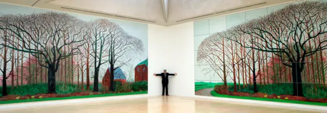 Hockney poses for photographers next to his 2007 painting Bigger Trees Near Water (L) which is dispalyed beside by an identical photographic copy at the Tate gallery in London.