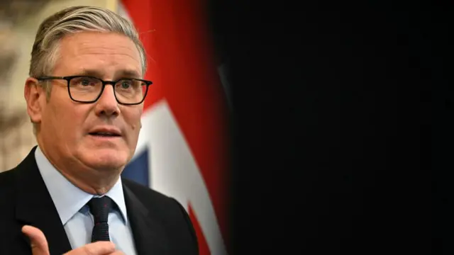 Starmer gestures as he speaks, with the right had side of the picture just blackness