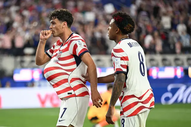 Giovanni Reyna celebrates by placing a football under his shirt and sucking his thumb