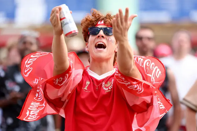 A person holds up their arms and is holding a beer can