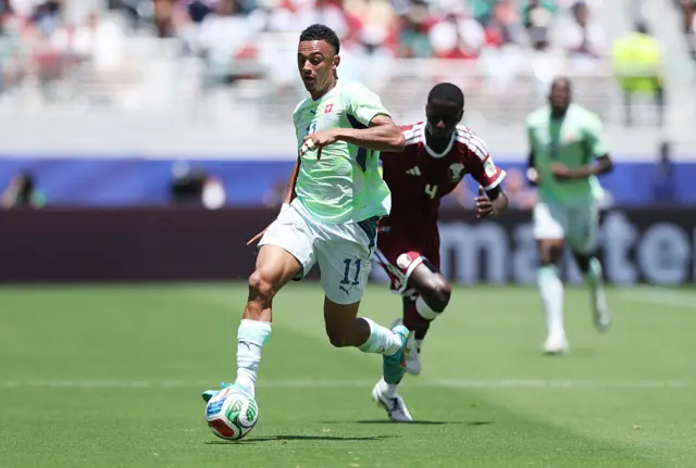 Dan Ndoye #11 of Switzerland controls the ball under pressure from Issa Laye #4 of Qatar