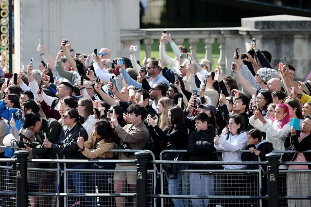 Onlookers gathered to watch the parade hold their phones and cameras up in the air.