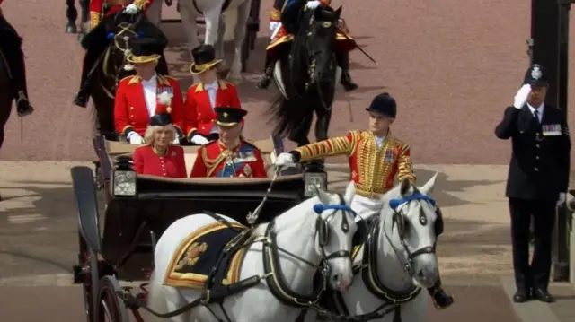 King Charles and Queen Camilla travelling in a horse-drawn carriage
