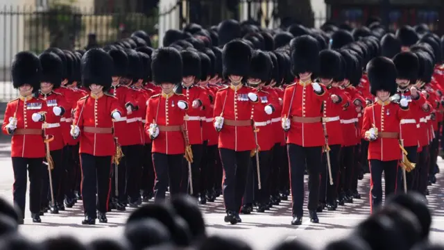 The Grenadier Guards match along The Mall holding swords in their red uniforms ahead of the Trooping the Colour ceremony