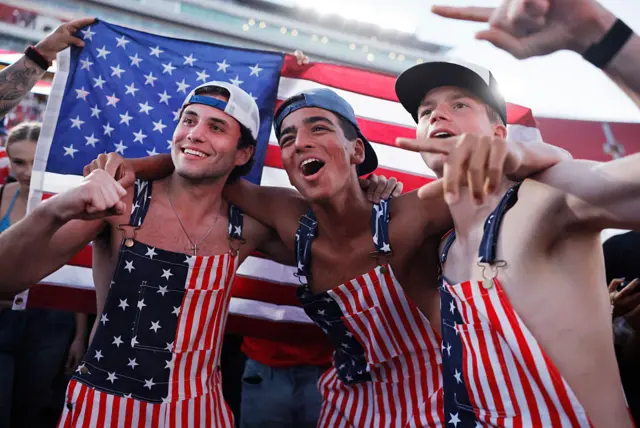 Three men wearing dungarees with the American flag