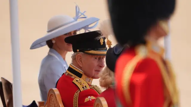 The King looks towards the Queen during the Trooping the Colour ceremony. The Princess of Wales can be seen sitting behind him