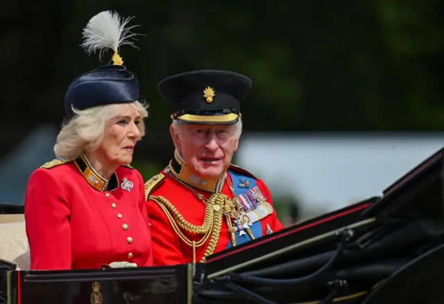 King Charles and Queen Camilla travelling in a horse-drawn carriage