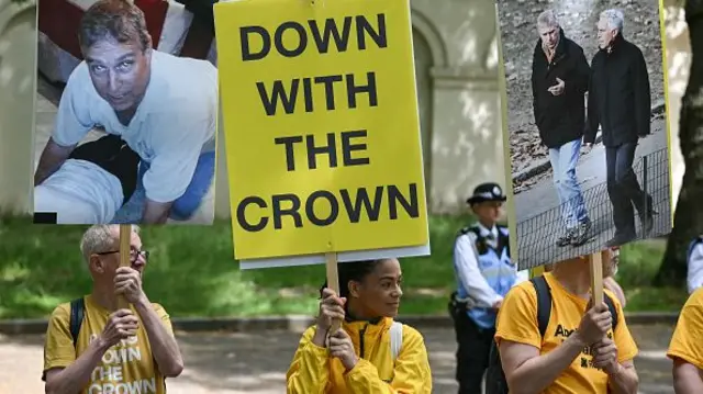Protesters hold placards showing the former Prince Andrew and late US sex offender Jeffrey Epstein during the Trooping the Colour