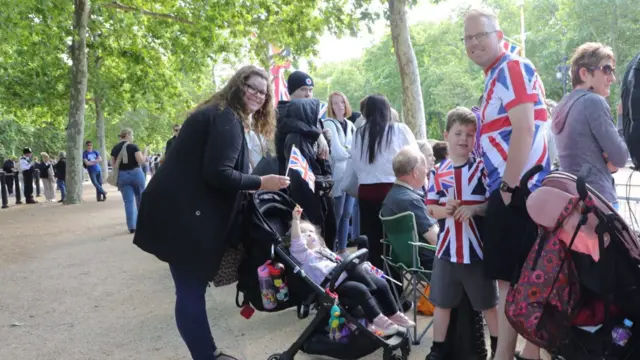 TIm and his children, one in a push chair, wear union shirts and stand near the barricade to watch the parade.