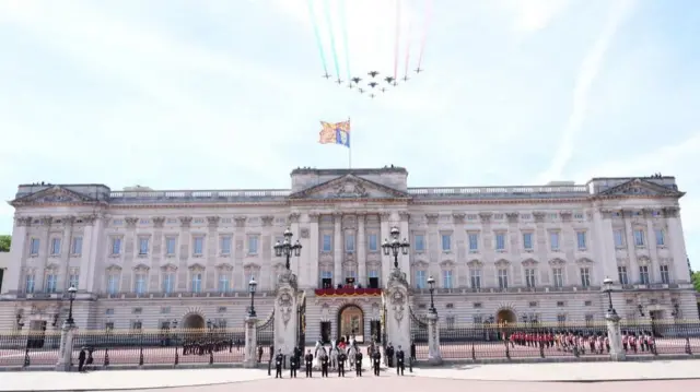 Buckingham Palace is pictured with the Red Arrows flying overhead, leaving a trail of red, white and blue.