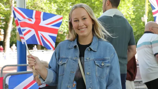 Karenna holds a union flag and wears a denim jacket.