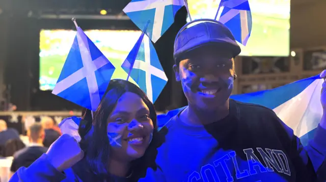 A smiling man and woman with Scotland flags
