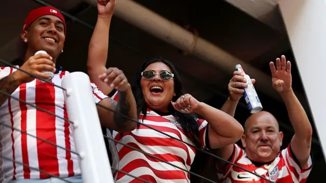 Three fans wearing USA fans dance for the camera.
