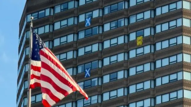 Scotland flags hanging out of hotel windows with a large USA flag in the foreground