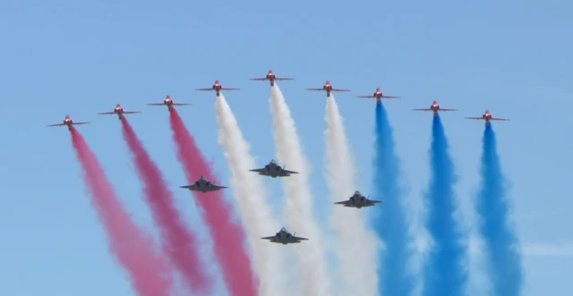 The Red Arrows send trails of red, white and blue through the air followed by four fighter jets in a diamond shape