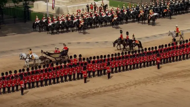 The King and Queen travel in a carriage passed lines of soldiers at Horseguards Parade, London.