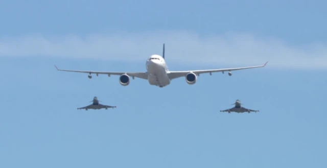 Military planes, including a pair of Typhoons, fly over The Mall and Buckingham Palace