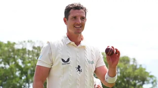 Keith Dudgeon celebrates taking six wickets for Kent by holding up the ball at the end of the Lancashire innings