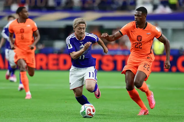 Daizen Maeda fights for the ball with Denzel Dumfries