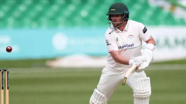 Lewis Hill looks at the ball as it passes over his stumps while batting