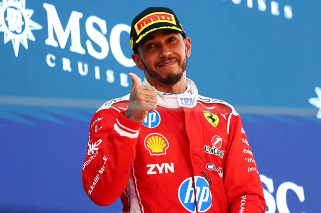 Lewis Hamilton gives a thumbs up on the podium