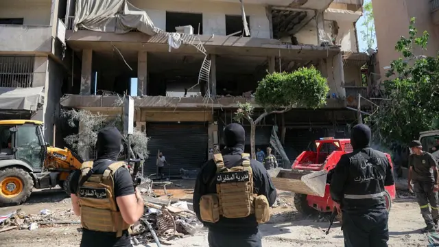 Lebanese army soldiers stand guard as people clear the rubble at the site of an Israeli airstrike that targeted a building in Beirut's southern suburbs on June 14, 2026