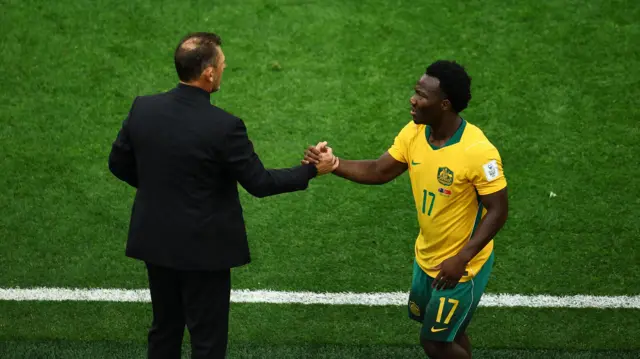 Australia's Nestory Irankunda shakes hands with coach Tony Popovic as he is substituted off